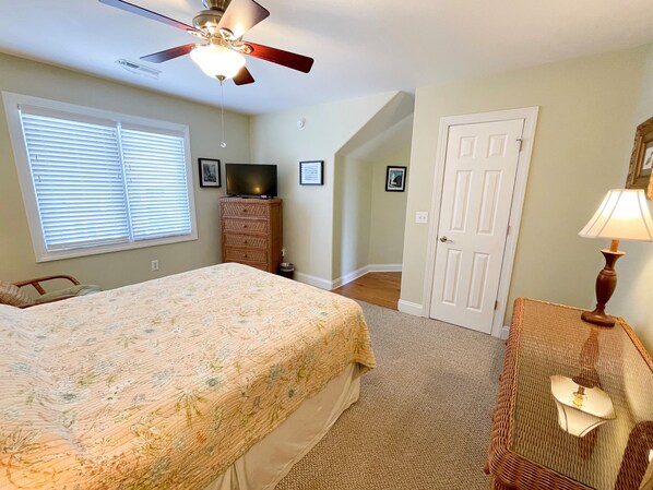 Un dormitorio con cama, cómoda, televisor y puerta.