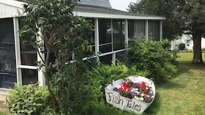 A house with a large window and a sign that reads "Fish Tales" in the front yard.