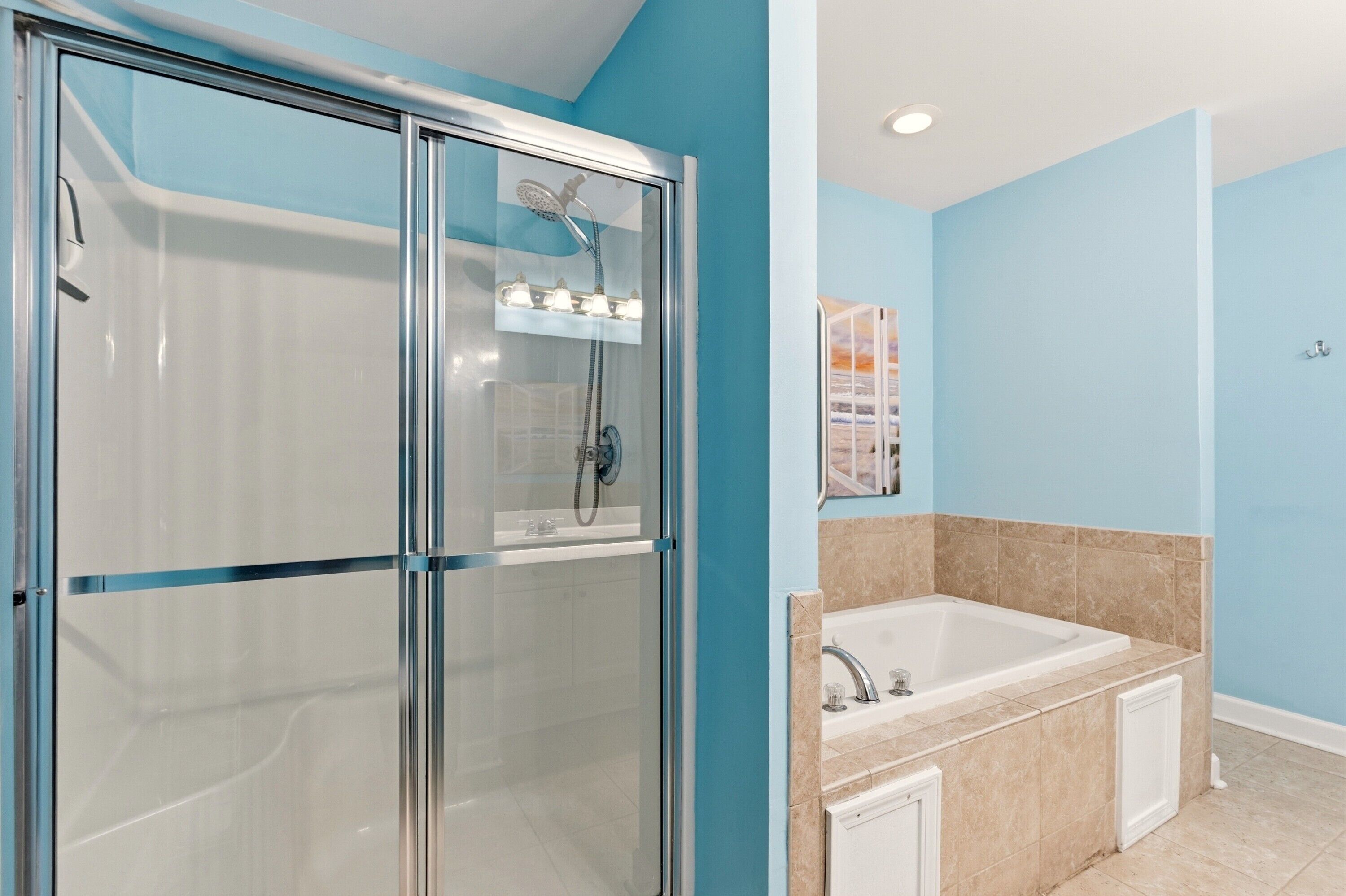 Un baño con mampara de vidrio, bañera y lavamanos.