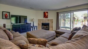 A living room with a sofa set, a flat-screen TV, a fireplace, and a view of the outdoors. - Las Palmas Resort #1511 | All-Inclusive Amenities (Saint George)