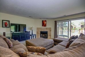 A living room with a sofa set, a flat-screen TV, a fireplace, and a view of the outdoors. - Las Palmas Resort #1511 | All-Inclusive Amenities (Saint George)