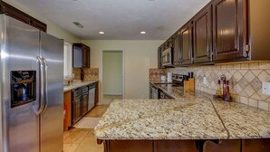 A kitchen with a stainless steel refrigerator, a microwave, and a granite countertop. - Las Palmas Resort #1511 | All-Inclusive Amenities (Saint George)