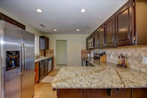 A kitchen with a stainless steel refrigerator, a microwave, and a granite countertop. - Las Palmas Resort #1511 | All-Inclusive Amenities (Saint George)