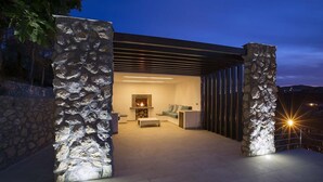 A modern outdoor living area with a stone wall, a fireplace, and a seating area.
