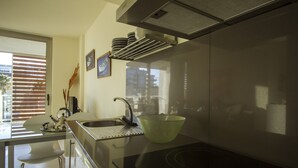 Een moderne keuken met een roestvrijstalen spoelbak, een glazen eettafel en een zwart fornuis.