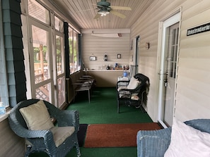 Relax in this inviting porch area with a bar, seating, and ceiling fan.