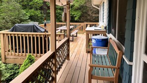 Um deck de madeira com mesa, cadeiras e churrasqueira.