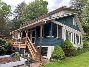 Stroll up to this charming two-story home, featuring a spacious porch and a balcony with a railing, surrounded by lush greenery.