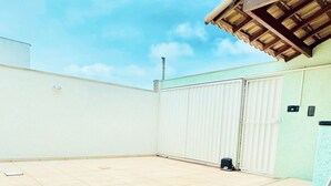 Ein Schwimmbad mit blauen Mosaikfliesen, einer weißen Wand und einem überdachten Bereich mit Holzdach.