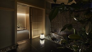 Un intérieur japonais traditionnel avec un sol recouvert de tatamis, une porte coulissante de type shoji et un élément décoratif aquatique en pierre.