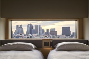 A hotel room with a large window overlooking a city skyline.