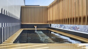 Un interior moderno con un estanque reflectante, paneles de madera y vistas a la ciudad.