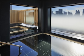 Ein modernes Interieur mit großen Fenstern, einem spiegelnden Boden und Blick auf eine Stadtlandschaft durch ein nebliges Fenster.
