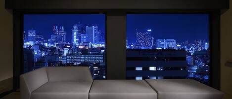 Un salón moderno con un ventanal que ofrece vistas nocturnas de la ciudad.