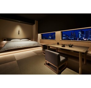 Relax in a serene space with a large bed, wooden desk, and city view.