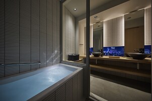 A modern bathroom with a large bathtub, a large mirror, and a cityscape view through the window.
