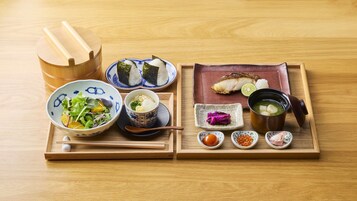 A wooden tray with various Japanese dishes including sushi, sashimi, and a bowl of soup.