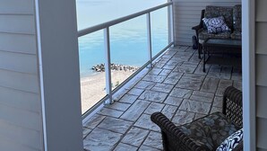A covered patio with a view of the ocean, stone flooring, and wicker furniture. - •Lake Erie Vista Dream Penthouse 4 Bed Room 2.5 Bath Private Beach & Indoor Pool (Geneva-on-the-Lake)