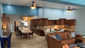 A spacious living area with a large brown sectional sofa, a dining table with chairs, and a kitchen area with wooden cabinets and a countertop. - •Lake Erie Vista Dream Penthouse 4 Bed Room 2.5 Bath Private Beach & Indoor Pool (Geneva-on-the-Lake)