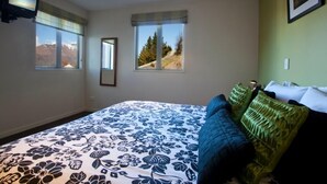 A bedroom with a bed, two windows, a television, and a framed picture on the wall. - Spectacular Views , Large & Modern , Perfect For Families & Large Groups (Queenstown)