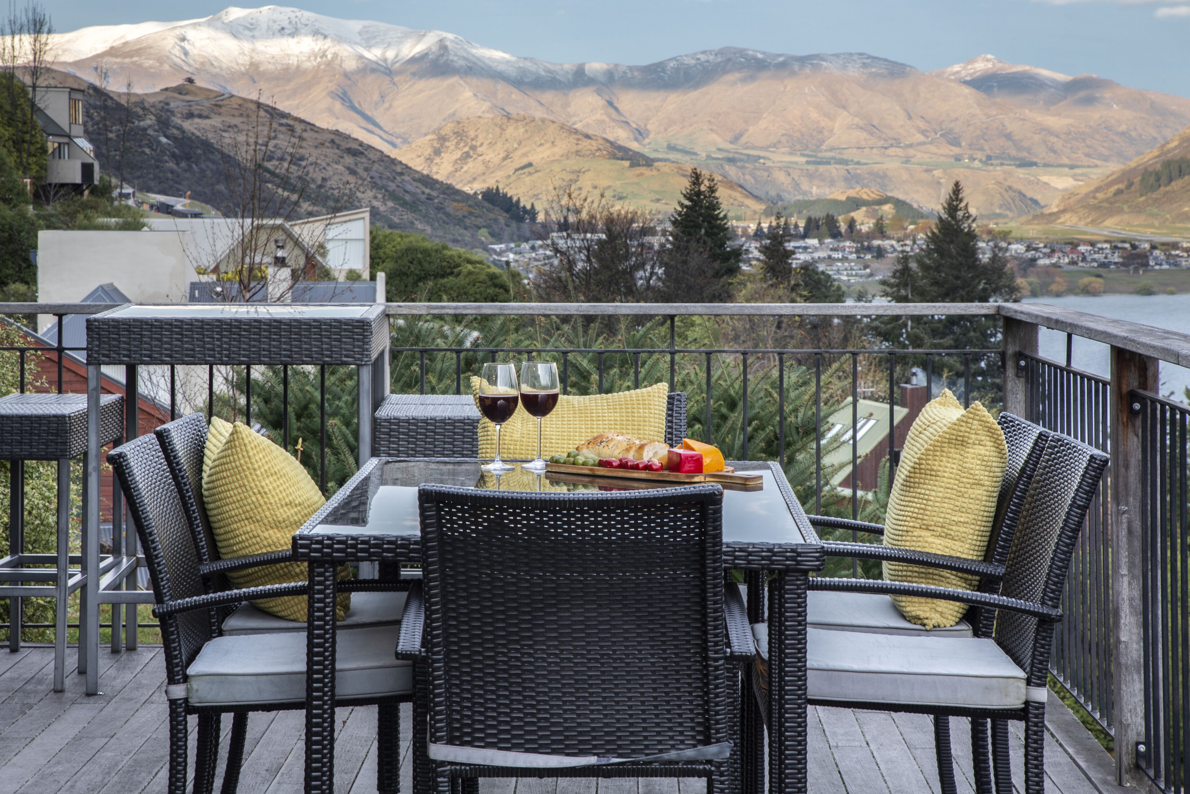 Une terrasse dotée de meubles en osier, d’une table en verre et offrant une vue sur des montagnes enneigées.
