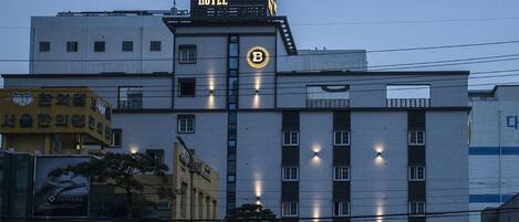 Un hotel con un cartel llamativo que dice 'Brown-Dot Hotel' y un gran logotipo iluminado con la letra 'B'.