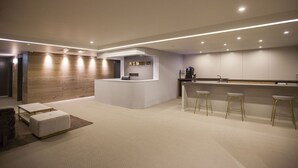 Una cocina moderna con una isla central, taburetes de bar y una pared decorativa de madera.