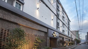 Fachada moderna de un hotel con un letrero que dice "Brown Dot Hotel".
