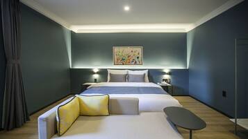 A modern hotel room with a large bed, a sofa, and a small table.