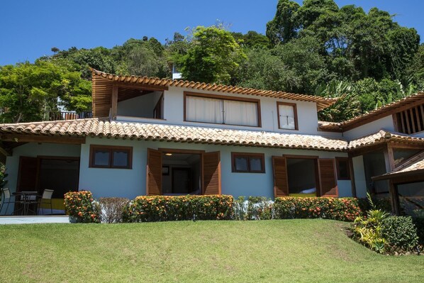 Una casa de dos pisos con techo de tejas, contraventanas de madera y un césped bien cuidado.