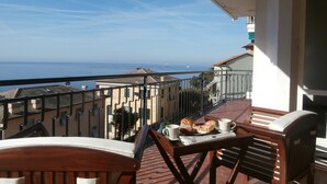 Ein Balkon mit Frühstückstisch, mit Blick auf die Küste.