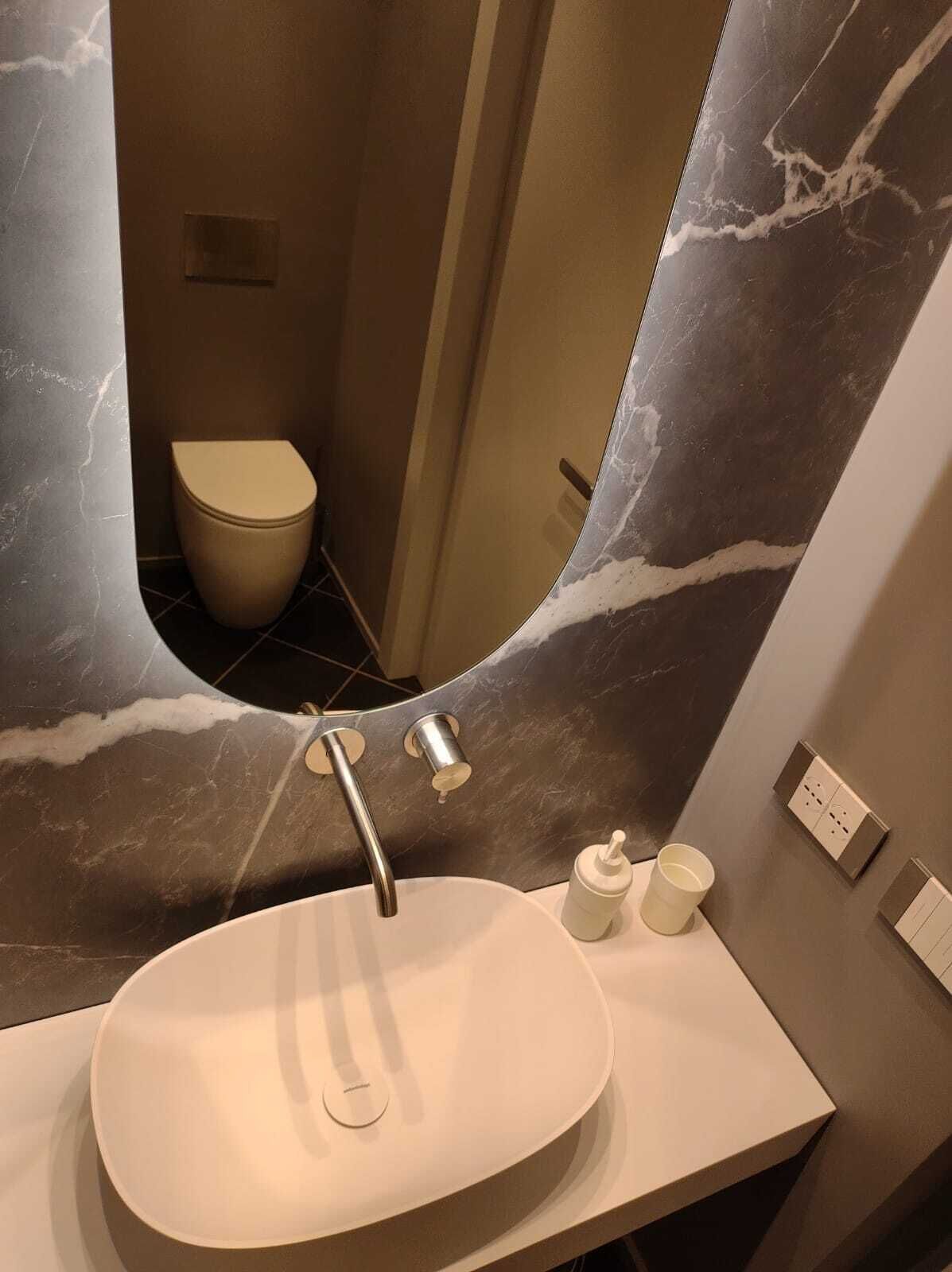 A bathroom with a marble sink, a toilet, and a mirror.