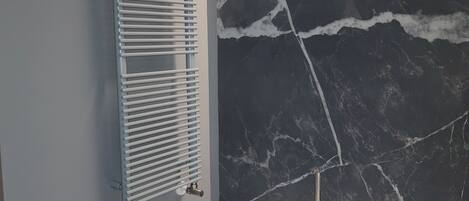 A bathroom with a white bathtub, a wall-mounted towel rack, and a marble-patterned wall.