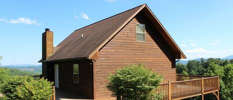 A wooden cabin with a porch, a chimney, and a deck.