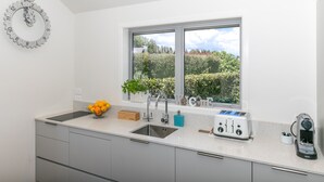 A modern kitchen with a large window, a sink, a toaster, and a kettle. - Spacious Modern Two-Bedroom Apartment (Tamahere)