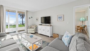 En moderne stue med sofa, sofabord og fjernsyn på et hvidt skab.
