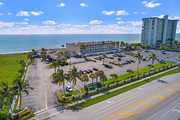 A hotel with a parking lot, a building with a flat roof, and a view of the ocean. - Beach Condo/ Island Beach Resort/ No Cleaning Fee/ Condo 401 (Jensen Beach)