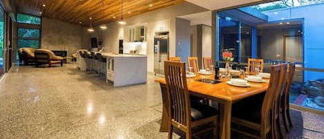 Cocina moderna con una isla central, comedor con sillas de madera y un ventanal con vistas a un paisaje rocoso.