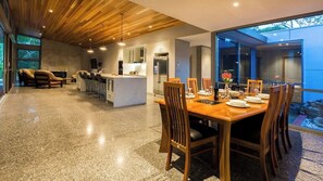 A modern kitchen with a central island, dining area with wooden chairs, and a large window overlooking a rocky landscape.