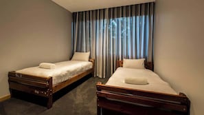 A room with two wooden beds, each with a pillow and a rolled towel.