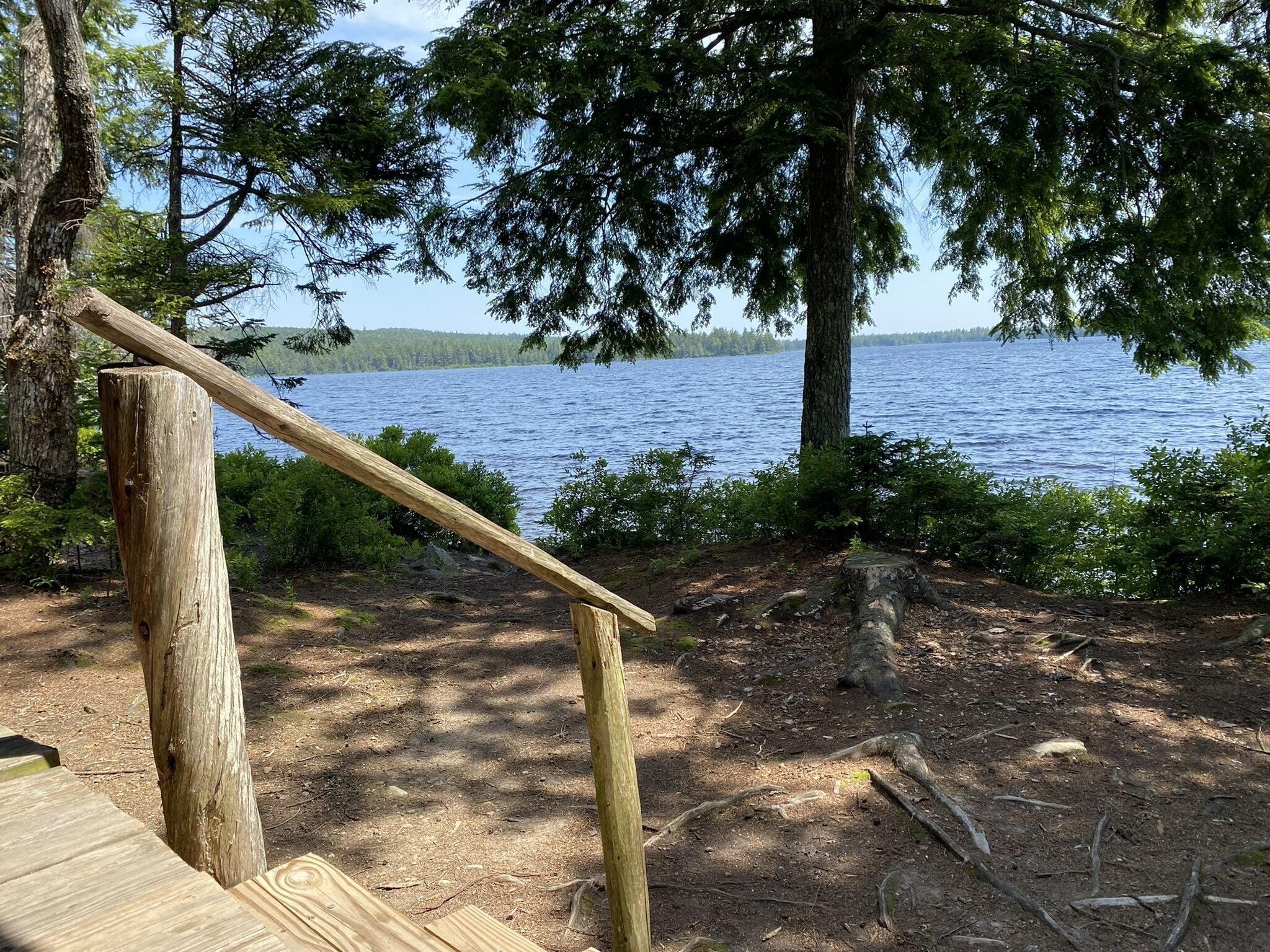 Ein Holzdeck mit Holzgeländer, das auf einen See blickt.