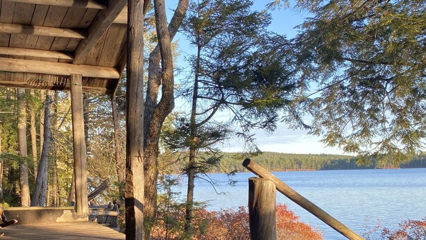 A wooden deck with a view of a lake and trees.