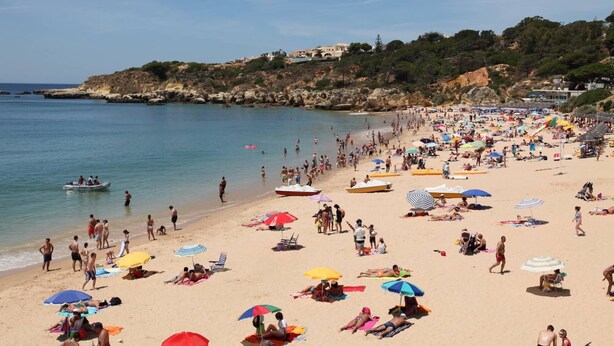 Une plage bondée, avec de nombreux parasols et des gens qui profitent du soleil.