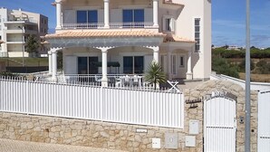 Un immeuble à plusieurs étages doté de balcons, d’une façade en pierre et d’une entrée fermée par un portail.