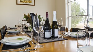 A dining table set with plates, cutlery, wine glasses, and bottles of wine. - Barossa Idyll- Accommodation for Groups (Tanunda)