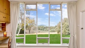 A room with a large window, a wooden cabinet, and a chair. - Barossa Idyll- Accommodation for Groups (Tanunda)