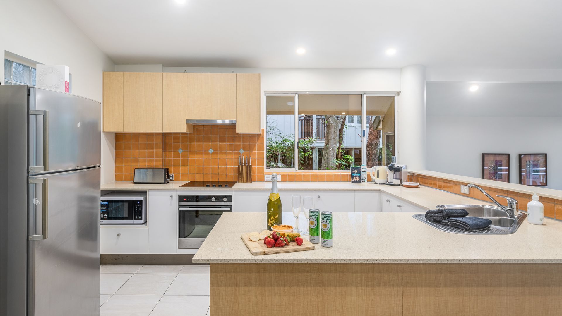 Una cocina moderna con electrodomésticos de acero inoxidable, una isla grande y vistas al exterior a través de una ventana.