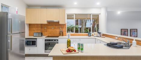 Una cocina moderna con electrodomésticos de acero inoxidable, una isla grande y vistas al exterior a través de una ventana.