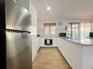 Une cuisine moderne dotée d’appareils électroménagers en acier inoxydable, de meubles blancs et d’un plancher en bois.