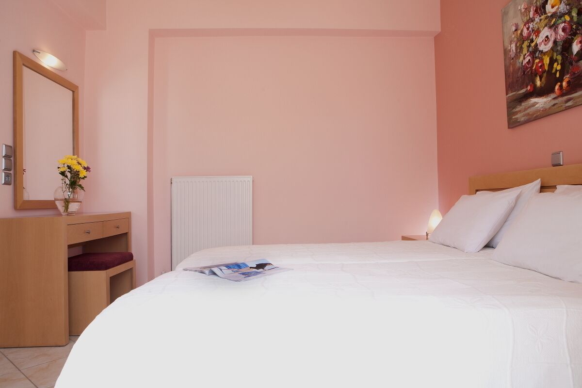 A bedroom with a bed, a dresser, a mirror, a radiator, and a painting on the wall.